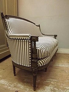 An antique settee reupholstered in ticking fabric. Historically, ticking was not used to cover fine furniture.