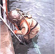 Diver in standard diving dress entering the water at Stoney Cove, England