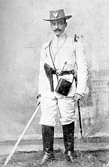 Mambí officer Carlos Manuel de Céspedes y Quesada holding a machete and wearing a holster for a pistol.