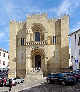 The Old Cathedral of Coimbra, Portugal, is fortress-like and battlemented. The two central openings are deeply recessed.