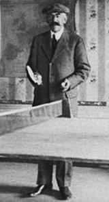 Lenglen's father standing behind a table tennis table