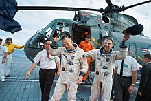 Astronauts in spacesuits exiting helicopter on aircraft carrier