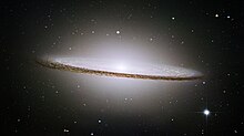 The dark band of the "dust lane" is clearly visible against the brighter background of stars within the Sombrero Galaxy.