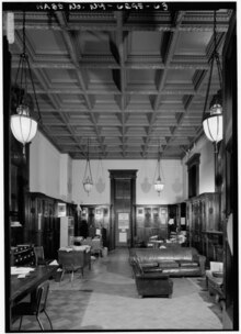 Black-and-white image of the Company A room, which is decorated with dark mahogany woodwork, a coffered ceiling, and a fireplace