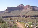View of Tower of Set peak and sub-unit cliff section from Tonto Trail, Granite Gorge, north of Mohave Point, Grand Canyon Village, South Rim. The peak is behind and separated from a cliff unit (with small prominence), in front-(photo center, right, Tower of Set (peak) to its left). Vertical erosion in cliff of Redwall Limestone, upon horizontal Muav Limestone cliff.[18] The Tapeats Sandstone sits in foreground on Granite Gorge, and is seen as thinly-bedded. The slope-former above is the (dull-greenish)-Bright Angel Shale with thin, inter-bedding, as well as one resistant cliff unit. The Redwall Limestone cliff section in Grand Canyon is about 450 feet (137 m) thick.[19]
