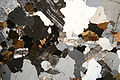 Granite in thin section under cross-polarized light in which feldspar crystals exhibit sericite alteration