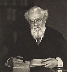 Photograph of Adolf Tobler, wearing spectacles and reading a book