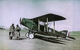 Two men in flying gear next to a military biplane