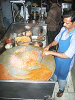 Pav bhaji being prepared on an iron tava