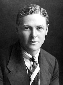 A head and shoulders photograph of a man in a suit and tie
