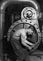Image 32Lewis Hine's 1920 image "Power house mechanic working on steam pump," which shows a working class young American man with wrench in hand, hunched over, surrounded by the machinery that defines his work.