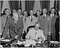 President Truman signs the National Security Act Amendment of 1949. Secretary of Defense Louis A. Johnson leans over the desk. Behind him is Admiral Louis Denfeld, General Omar N. Bradley, and General Hoyt Vandenberg.