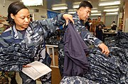 YN1 Latricia Perkins (left), assigned to the Administration Department at Naval Air Facility Atsugi, Japan, sorts through a pile of the new Navy Working Uniforms.