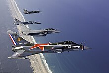 Four fighter planes in formation along a coastline