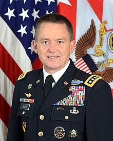 A man in a military uniform in front of flags