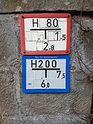 Red fire hydrant marker plate in Germany, along with another blue special-purpose water hydrant marker plate – The numbers indicate the diameter (80 mm) and the location (2.8 meter in the back, 1.5 meter to the right).