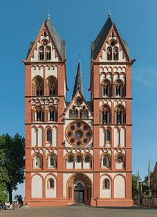 Limburg Cathedral, Germany. The façade, c. 1200, with polychrome plaster, follows the paired-tower model found at several Rhineland churches. The rose window has plate tracery and the spires are Rhenish helms.