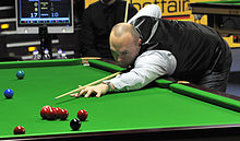 Photograph of Stewart Bingham leaning over a snooker table looking down his cue