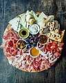 Italian circle setting with cold cuts and cheeses and some nuts and grape and breads with sauce dressing
