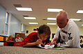 Petty Officer 2nd Class Jeff Kline, helps a child with homework at the Cameron Community Ministries after school program during Rochester Navy week