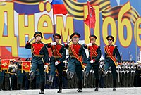 Honour guard marching with the Russian flag and the Victory Banner