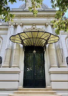 Wrought iron door with a glass and metal awning at the top, at the entrance of the George Deșliu House on Bulevardul Dacia, Bucharest, by Ernest Doneaud, 1912[52]