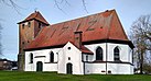 Seitenansicht der Dorfkirche von Berghusen, mit geweißten Seitenwänden und rotem Ziegeldach, der mit rotem Backstein gemauerte Kirchturm befindet sich links.
