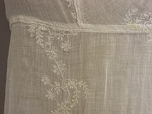 Detail of white embroidery in a floral design on a white muslin dress, circa 1805