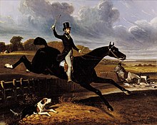 Man on a large black horse jumping a fence and ditch in a rural setting