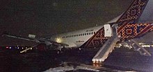 an aircraft disabled on a runway in the dark, with evacuation slides deployed