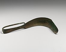 A curved metal object with a handle and a dull blade used to scrape oil