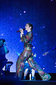 Lorde looking sideways as she performs onstage in a sheer coloured outfit