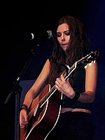 Marion Raven, a young brunette woman, playing a guitar on stage