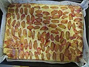 Sheet pan with sliced plums laid across the cake batter