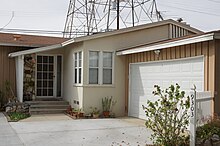 bungalow with an attached garage, with a tower and power lines in the background
