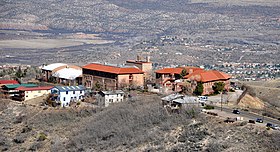 A cluster of buildings with orange slate roofs, seen from a hill above