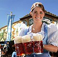Eine Kellnerin mit drei Maß Bier. Sie trägt ein bayerisches Dirndl.