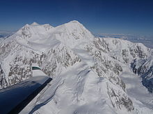 An aerial view of Denali; an airplane wing is visible in the lower-left corner