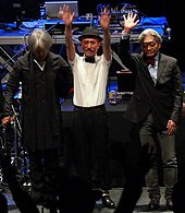 A colour photograph of three members of Yellow Magic Orchestra at the front of a stage