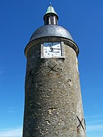 A circular Medieval stone tower with a clock near the top