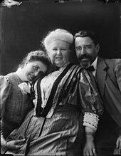 Two women and a man dressed in the fashions of the Edwardian era