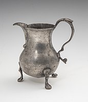 An ornate pewter cream pitcher