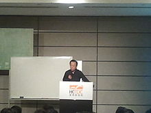 Yi giving a talk at the Hong Kong Convention and Exhibition Centre in July 2013