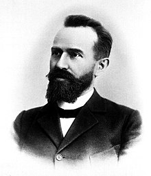 A three-quarter profile of Swiss psychiatrist Eugen Bleuler wearing a dark suit and with a long black beard.