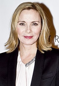 An image of a blonde woman wearing a black jacket and white dress shirt.