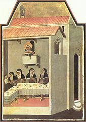 Five nuns eating in a dining hall with a senior nun watching over them from above