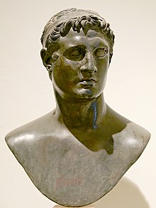 Dark stone bust of a young man wearing a headband