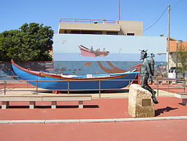 Traditional fishing boat and a sculpture of a diver, in the beach resort Aguda