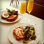 A homemade brunch consisting of cooked eggs on toast and salad, accompanied by orange juice