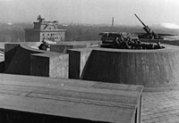 Auf dem Dach des Flakturms am Zoo: vorn Kommandogerät (optischer Entfernungsmesser), dahinter ein schweres Flak-Geschütz. Im Hintergrund der Leitturm mit dem Würzburg-Riese-Radargerät, in der Ferne die Siegessäule.